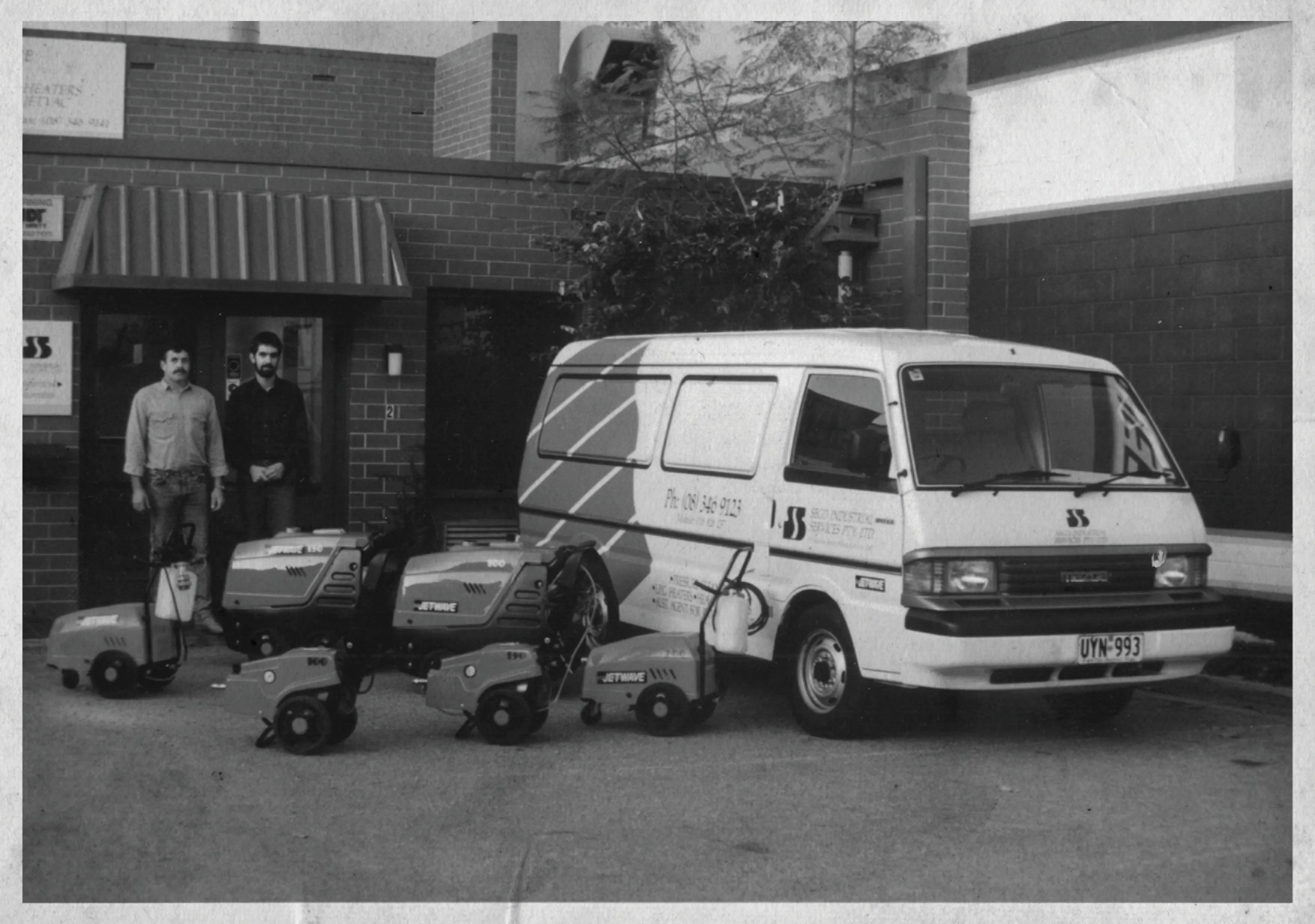 Black and white photo of vans and machines belonging to Seco Industrial Services.